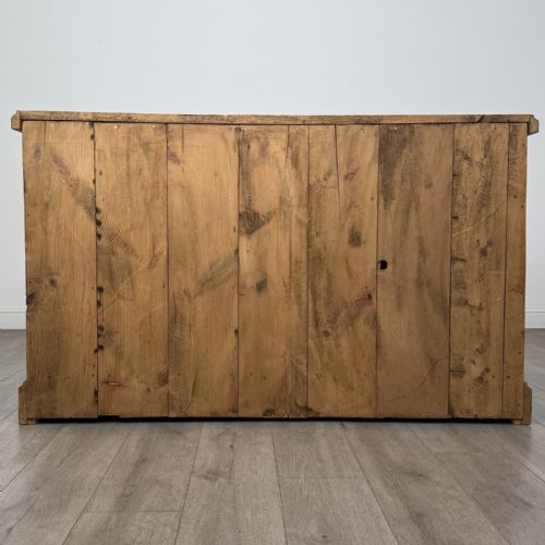 fig 4. A vintage natural pine sideboard featuring three top drawers above three panelled cupboard doors with turned wooden knobs and a solid plinth base.