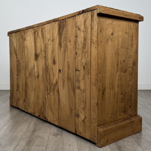 fig 5. A vintage natural pine sideboard featuring three top drawers above three panelled cupboard doors with turned wooden knobs and a solid plinth base.