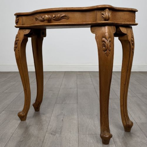 fig 1. A light oak French-style console table featuring a serpentine front, carved relief details on the apron, and cabriole legs.