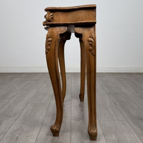fig 2. A light oak French-style console table featuring a serpentine front, carved relief details on the apron, and cabriole legs.