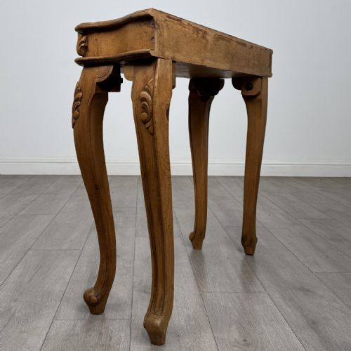 fig 3. A light oak French-style console table featuring a serpentine front, carved relief details on the apron, and cabriole legs.