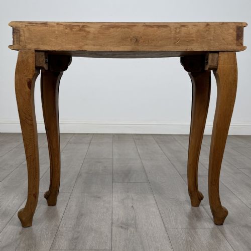fig 4. A light oak French-style console table featuring a serpentine front, carved relief details on the apron, and cabriole legs.
