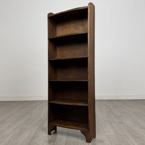 fig 1. A tall, narrow dark oak open bookcase featuring five bow-fronted shelves and a curved gallery top.
