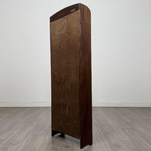 fig 5. A tall, narrow dark oak open bookcase featuring five bow-fronted shelves and a curved gallery top.