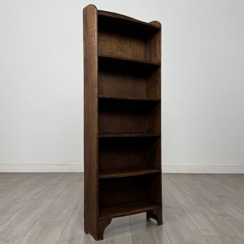 fig 7. A tall, narrow dark oak open bookcase featuring five bow-fronted shelves and a curved gallery top.