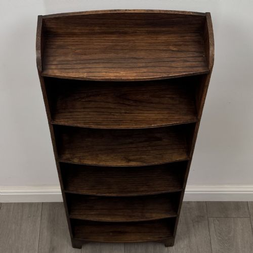 fig 8. A tall, narrow dark oak open bookcase featuring five bow-fronted shelves and a curved gallery top.