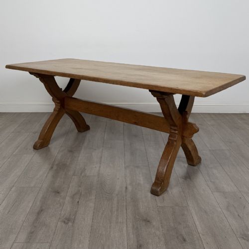 fig 1. A large 20th-century oak dining table featuring a rectangular wooden top supported by two trestle-style X-frame legs joined by a central horizontal stretcher.