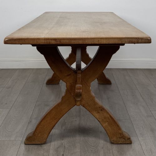 fig 2. A large 20th-century oak dining table featuring a rectangular wooden top supported by two trestle-style X-frame legs joined by a central horizontal stretcher.