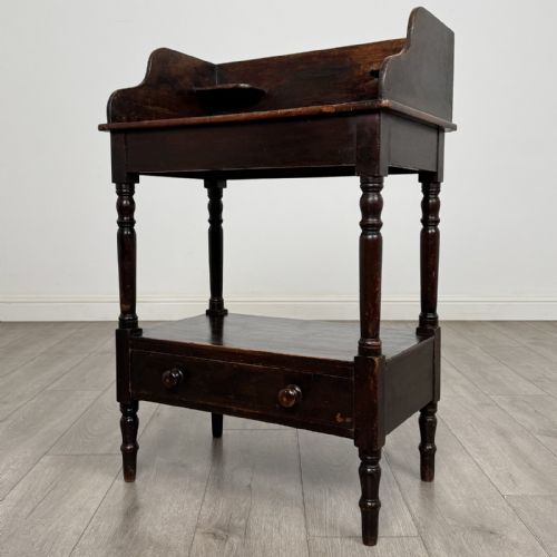 fig 1. A dark stained Victorian pine washstand featuring a three-quarter gallery back, turned legs, a lower shelf, and a base drawer with two turned wooden knobs.