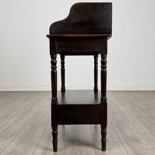 fig 2. A dark stained Victorian pine washstand featuring a three-quarter gallery back, turned legs, a lower shelf, and a base drawer with two turned wooden knobs.