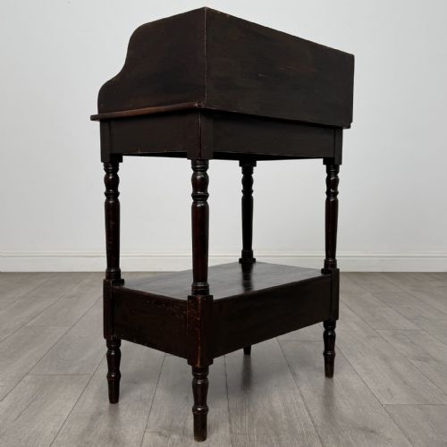fig 3. A dark stained Victorian pine washstand featuring a three-quarter gallery back, turned legs, a lower shelf, and a base drawer with two turned wooden knobs.