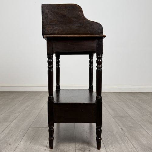 fig 6. A dark stained Victorian pine washstand featuring a three-quarter gallery back, turned legs, a lower shelf, and a base drawer with two turned wooden knobs.