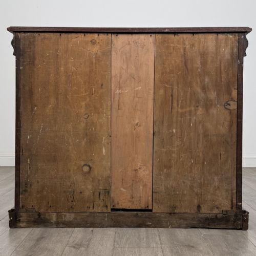 fig 4. An antique Victorian dark mahogany side cabinet featuring double arched panel doors, flanking turned columns, a plinth base, and a concealed frieze drawer.