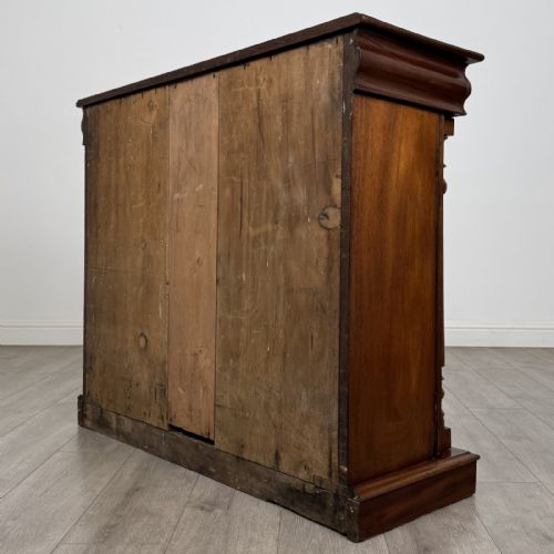 fig 5. An antique Victorian dark mahogany side cabinet featuring double arched panel doors, flanking turned columns, a plinth base, and a concealed frieze drawer.