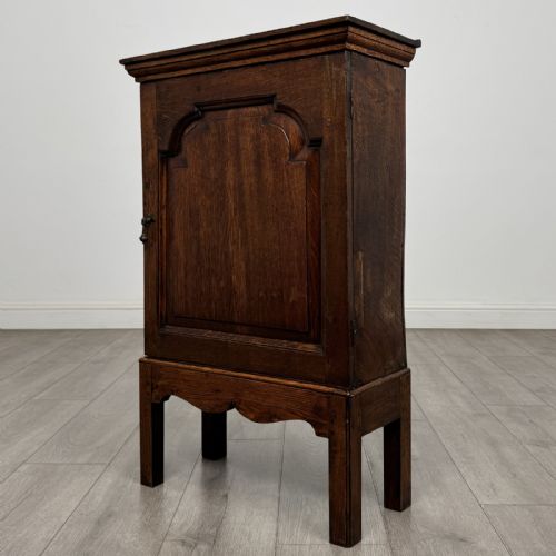 fig 1. A small dark Georgian oak spice cupboard on a stand with an arched fielded panel door and brass keyhole.