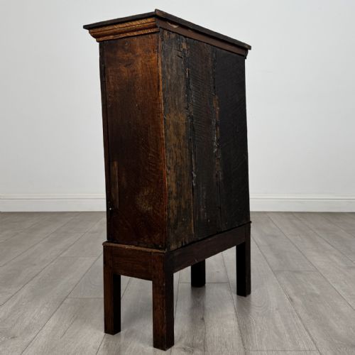fig 3. A small dark Georgian oak spice cupboard on a stand with an arched fielded panel door and brass keyhole.