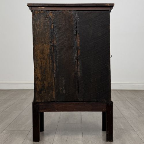 fig 4. A small dark Georgian oak spice cupboard on a stand with an arched fielded panel door and brass keyhole.