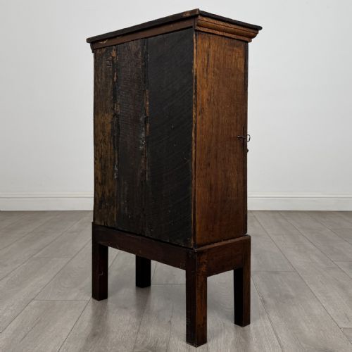 fig 5. A small dark Georgian oak spice cupboard on a stand with an arched fielded panel door and brass keyhole.