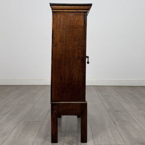 fig 6. A small dark Georgian oak spice cupboard on a stand with an arched fielded panel door and brass keyhole.