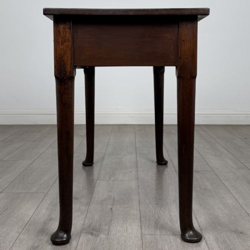 fig 2. A dark mahogany Georgian style side table featuring three drawers with ornamental brass handles and four tapered legs with pad feet.