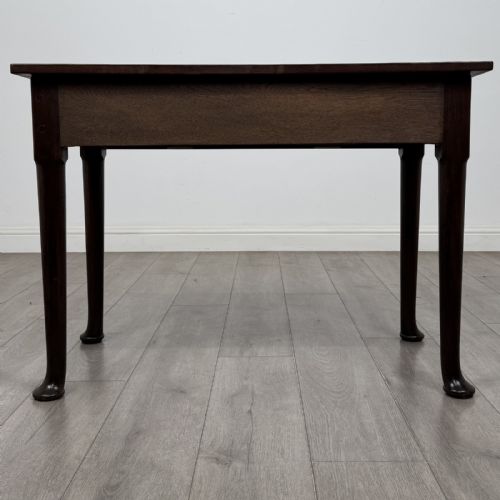 fig 4. A dark mahogany Georgian style side table featuring three drawers with ornamental brass handles and four tapered legs with pad feet.
