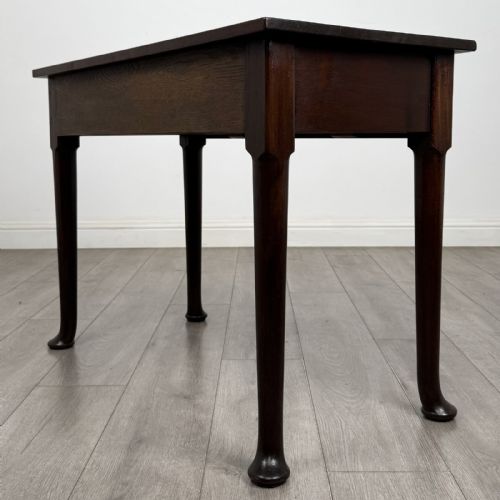 fig 5. A dark mahogany Georgian style side table featuring three drawers with ornamental brass handles and four tapered legs with pad feet.