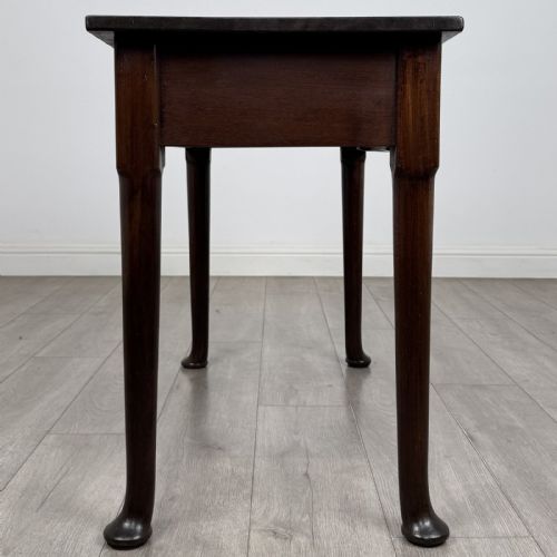 fig 6. A dark mahogany Georgian style side table featuring three drawers with ornamental brass handles and four tapered legs with pad feet.
