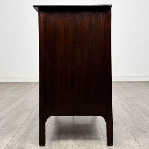 fig 2. A dark mahogany Arts and Crafts chest of drawers with three drawers, circular brass ring handles, and a central circular motif.