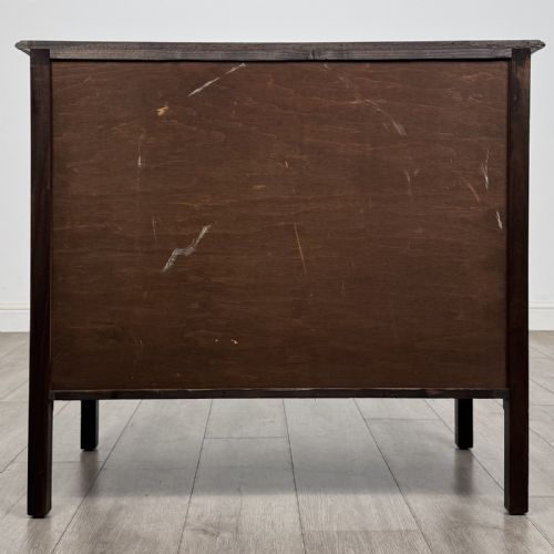 fig 4. A dark mahogany Arts and Crafts chest of drawers with three drawers, circular brass ring handles, and a central circular motif.
