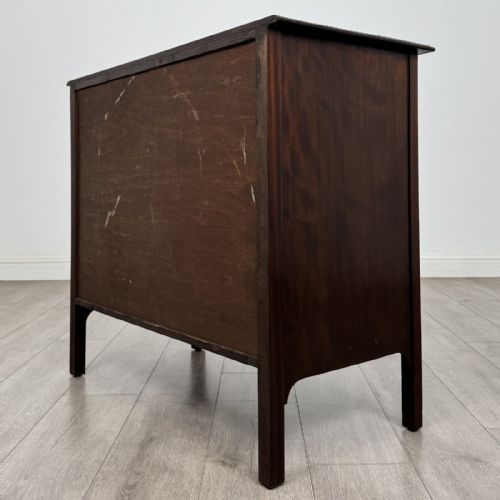 fig 5. A dark mahogany Arts and Crafts chest of drawers with three drawers, circular brass ring handles, and a central circular motif.