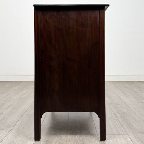 fig 6. A dark mahogany Arts and Crafts chest of drawers with three drawers, circular brass ring handles, and a central circular motif.