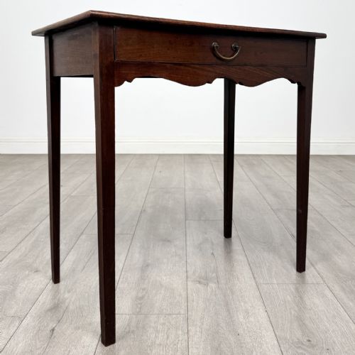 fig 7. An 18th-century Georgian mahogany side table with a single frieze drawer, brass handle, shaped apron, and straight square legs.