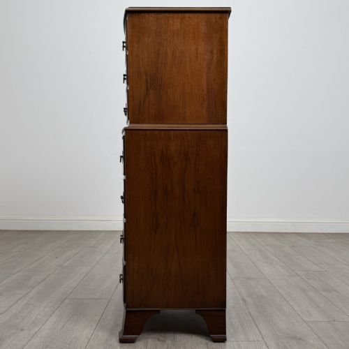 fig 2. A Georgian style burr walnut tallboy featuring a bow-front silhouette, seven stacked drawers with brass handles, and bracket feet.