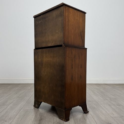fig 5. A Georgian style burr walnut tallboy featuring a bow-front silhouette, seven stacked drawers with brass handles, and bracket feet.