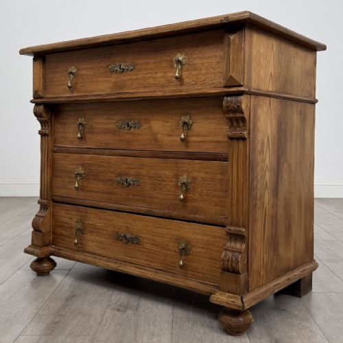 fig 1. An antique Victorian pine chest of four drawers featuring ornamental metal drop handles and carved architectural pilasters on turned feet.