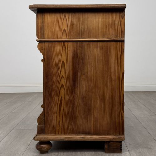 fig 2. An antique Victorian pine chest of four drawers featuring ornamental metal drop handles and carved architectural pilasters on turned feet.