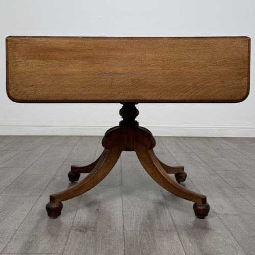 fig 1. A 19th-century solid oak Pembroke table with drop-down leaves, a single frieze drawer with turned wooden knobs, and a turned pedestal supported by four splayed sabre legs.