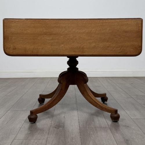fig 5. A 19th-century solid oak Pembroke table with drop-down leaves, a single frieze drawer with turned wooden knobs, and a turned pedestal supported by four splayed sabre legs.