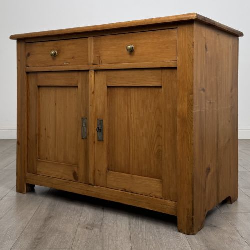 fig 1. A Victorian stripped pine cupboard featuring two top drawers with brass knobs above two panelled doors.