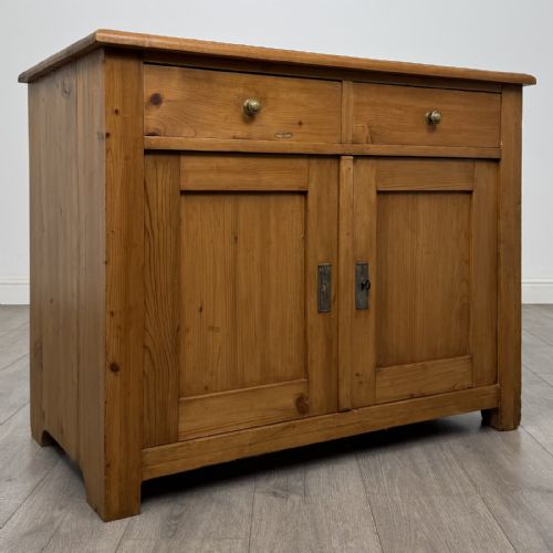fig 7. A Victorian stripped pine cupboard featuring two top drawers with brass knobs above two panelled doors.