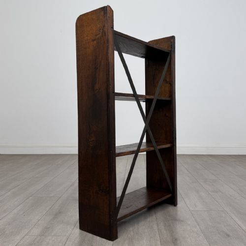 fig 2. An open dark oak bookcase featuring three shelves and a black iron cross back stretcher.