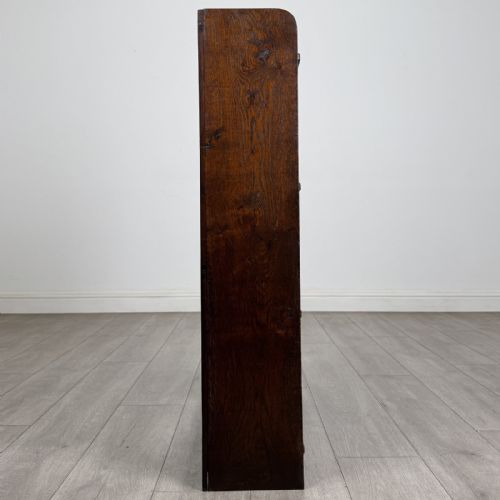 fig 5. An open dark oak bookcase featuring three shelves and a black iron cross back stretcher.