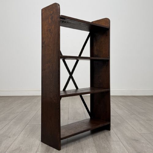 fig 6. An open dark oak bookcase featuring three shelves and a black iron cross back stretcher.