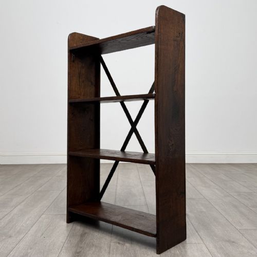 fig 7. An open dark oak bookcase featuring three shelves and a black iron cross back stretcher.