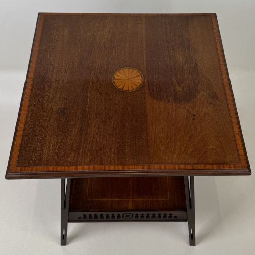 fig 6. An Edwardian dark mahogany lamp table featuring splayed legs with elongated vertical cutouts and a lower shelf enclosed by a carved fretwork gallery.