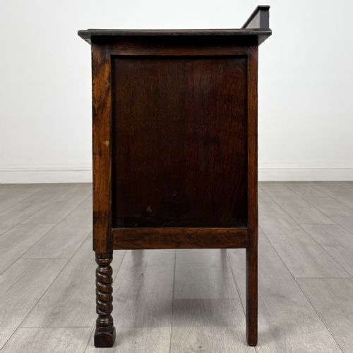 fig 2. A dark oak chest of drawers featuring three full-width drawers with metal drop handles and front barley twist legs.