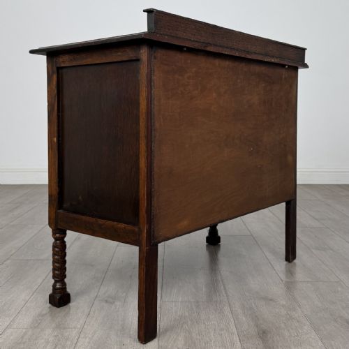 fig 3. A dark oak chest of drawers featuring three full-width drawers with metal drop handles and front barley twist legs.