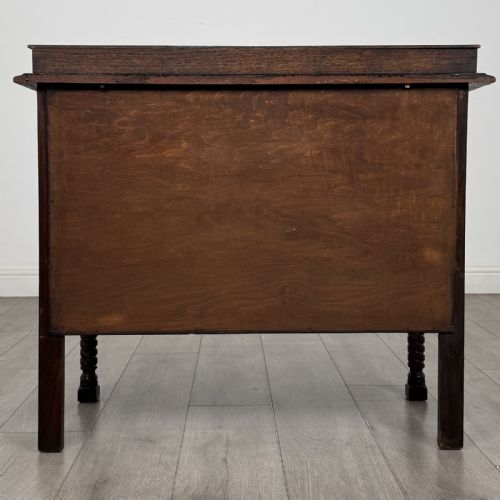 fig 4. A dark oak chest of drawers featuring three full-width drawers with metal drop handles and front barley twist legs.