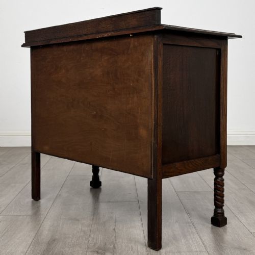 fig 5. A dark oak chest of drawers featuring three full-width drawers with metal drop handles and front barley twist legs.
