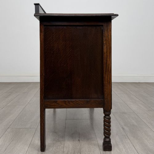 fig 6. A dark oak chest of drawers featuring three full-width drawers with metal drop handles and front barley twist legs.
